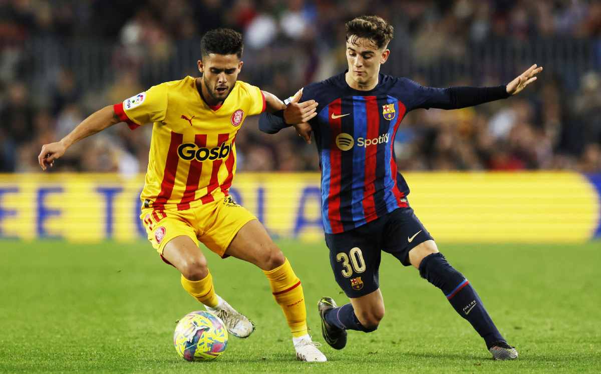 Jugador del Girona controla el balón ante la marca de un jugador del Barca.