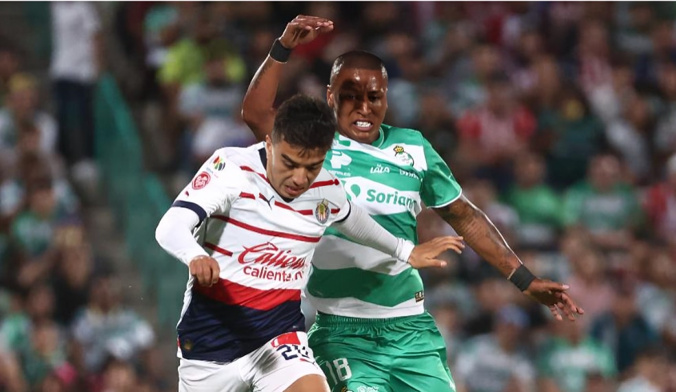 JUGADORES DE CHIVAS Y SANTOS COMPITEN POR EL BALÓN EN UN PARTIDO EN LIGA MX