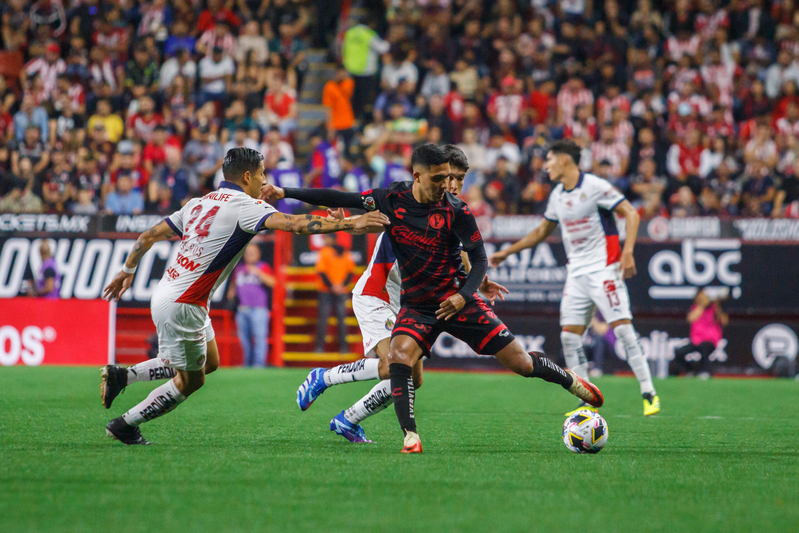 JUGADOR DE CHIVAS CONTROLA EL BALÓN ANTE LA DEFENSA DE CHIVAS